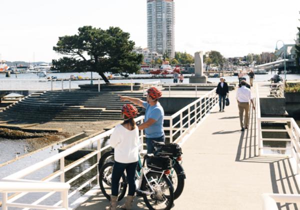 two adult cyclists stop on the waterfront pathway to take in the view